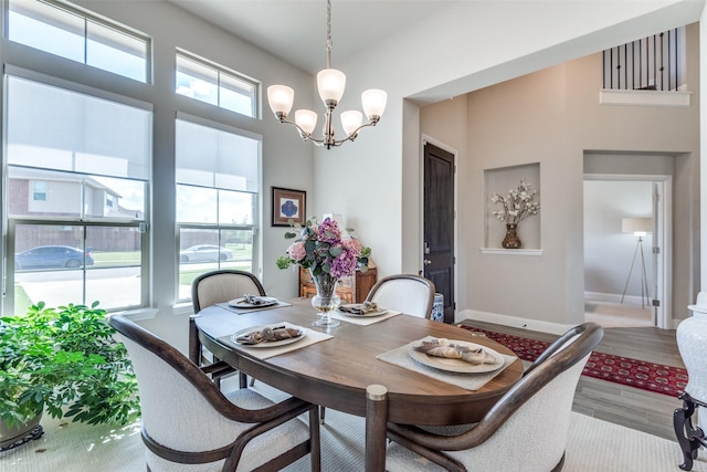 dining room with a chandelier, baseboards, and wood finished floors