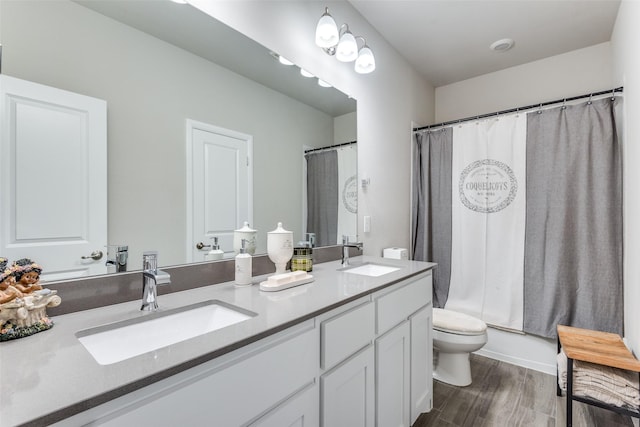 full bathroom featuring wood finished floors, a sink, toilet, and double vanity