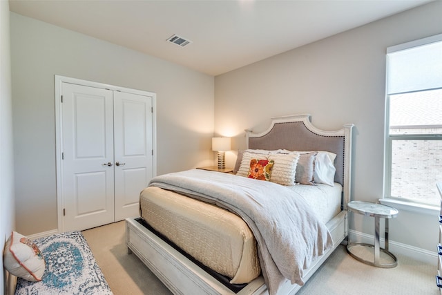 bedroom featuring a closet, light colored carpet, visible vents, and baseboards