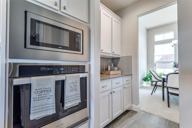 kitchen featuring stainless steel appliances, light countertops, white cabinets, and tasteful backsplash