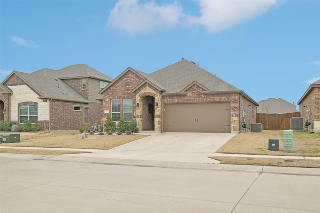 french country home with central AC, brick siding, and concrete driveway