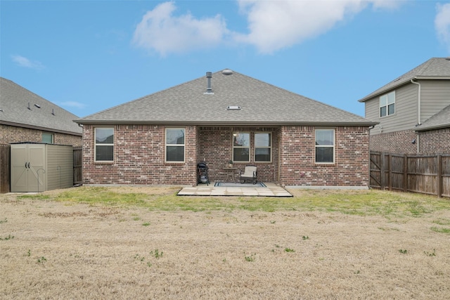 rear view of house featuring an outbuilding, a fenced backyard, a storage shed, brick siding, and a patio area