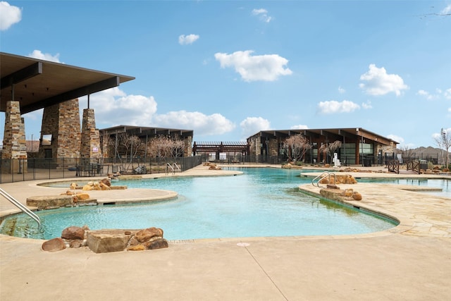 pool with a patio, fence, and a hot tub