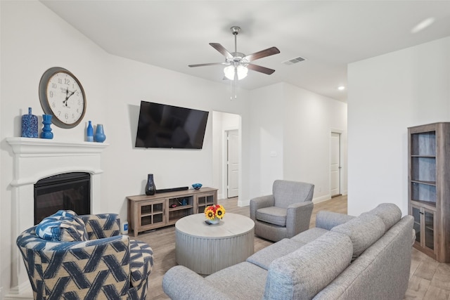 living area with visible vents, a glass covered fireplace, light wood-style flooring, ceiling fan, and recessed lighting