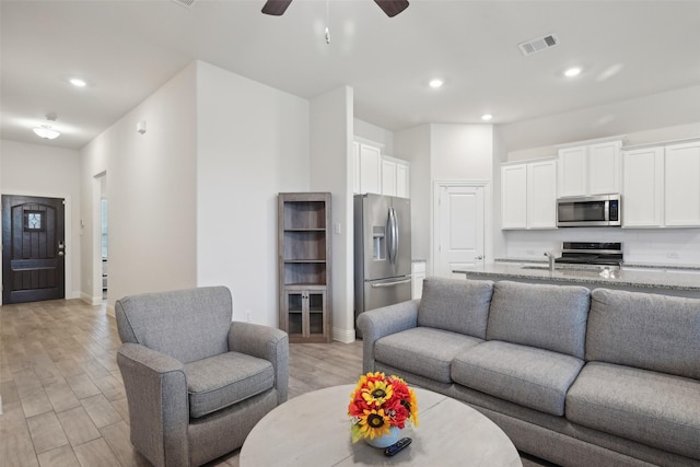 living room featuring visible vents, baseboards, light wood-style flooring, ceiling fan, and recessed lighting