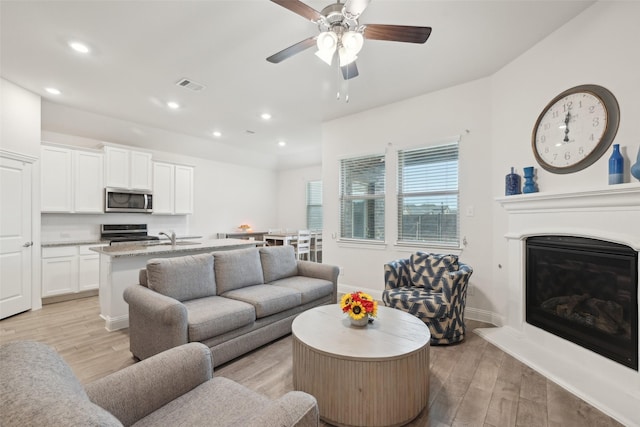 living area featuring baseboards, light wood-type flooring, visible vents, and recessed lighting