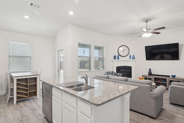 kitchen featuring visible vents, dishwasher, open floor plan, light wood-style floors, and a sink