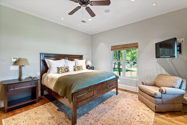 bedroom with crown molding, wood finished floors, visible vents, and baseboards