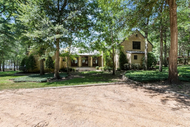 view of front facade with stone siding and a front lawn