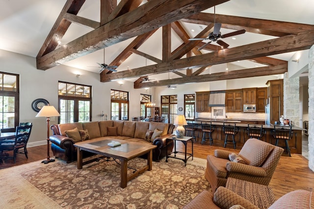 living area featuring plenty of natural light, a ceiling fan, light wood-style flooring, and beam ceiling