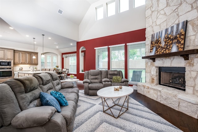 living room featuring a healthy amount of sunlight, visible vents, a fireplace, and wood finished floors