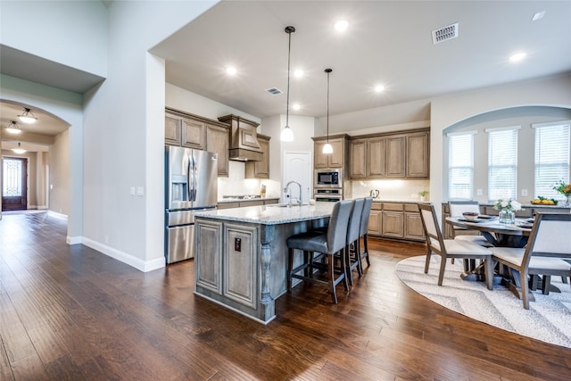 kitchen featuring visible vents, an island with sink, dark wood-style floors, stainless steel appliances, and a sink