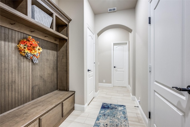 mudroom with baseboards, visible vents, and arched walkways