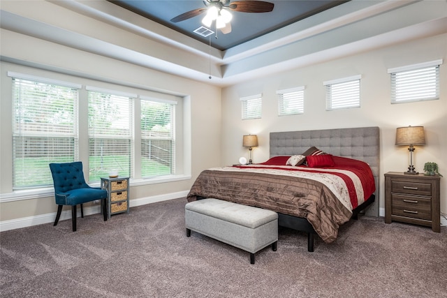 bedroom with carpet floors, a tray ceiling, visible vents, and baseboards