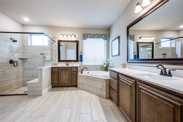 full bath with a stall shower, two vanities, a sink, and a bath