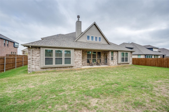 rear view of property with a fenced backyard, brick siding, a shingled roof, a yard, and a patio area