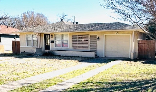 view of front of house with a front lawn, roof with shingles, fence, and an attached garage