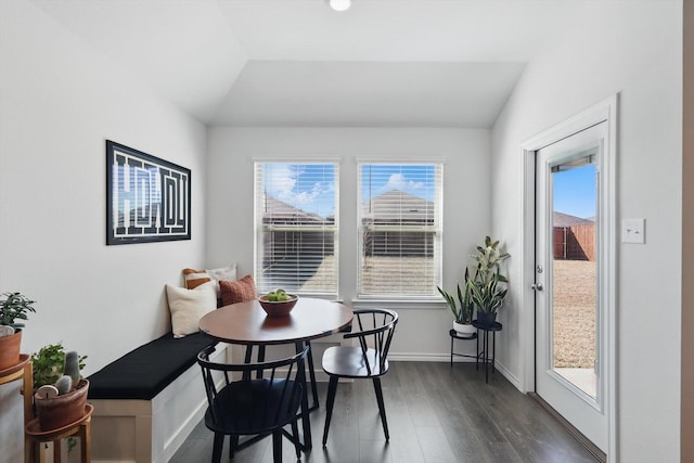 dining room featuring breakfast area, lofted ceiling, dark wood-type flooring, and baseboards