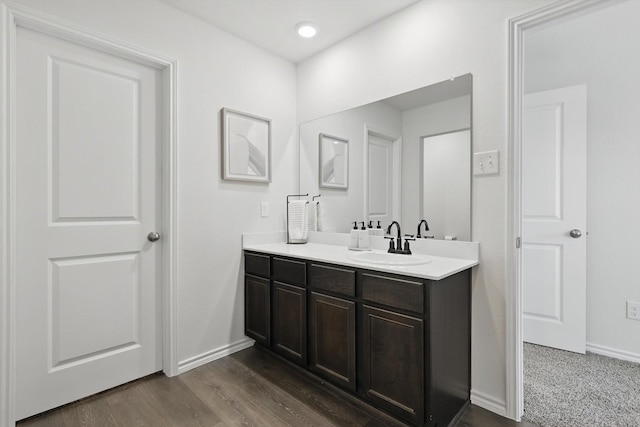 bathroom with recessed lighting, vanity, baseboards, and wood finished floors