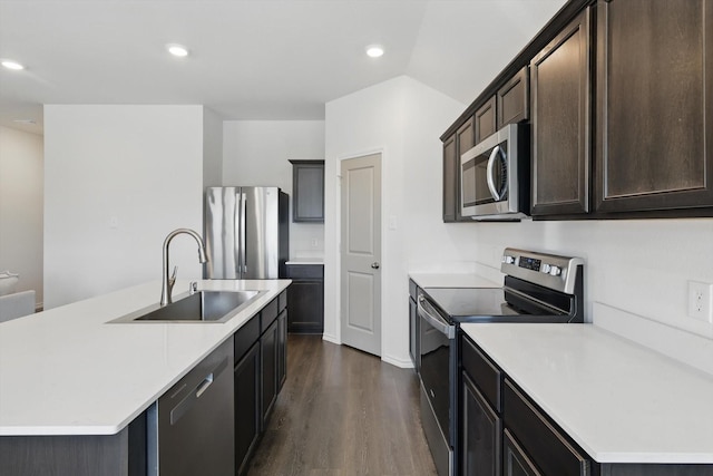 kitchen with a sink, light countertops, appliances with stainless steel finishes, an island with sink, and dark wood finished floors