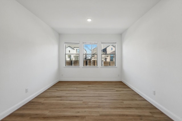 empty room featuring recessed lighting, baseboards, and light wood finished floors