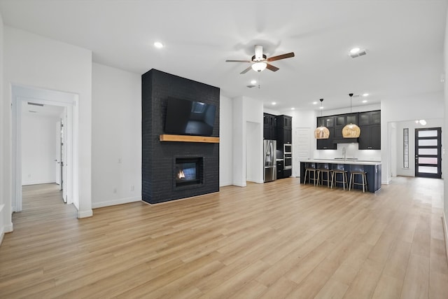 living area with a fireplace, light wood finished floors, recessed lighting, visible vents, and a ceiling fan