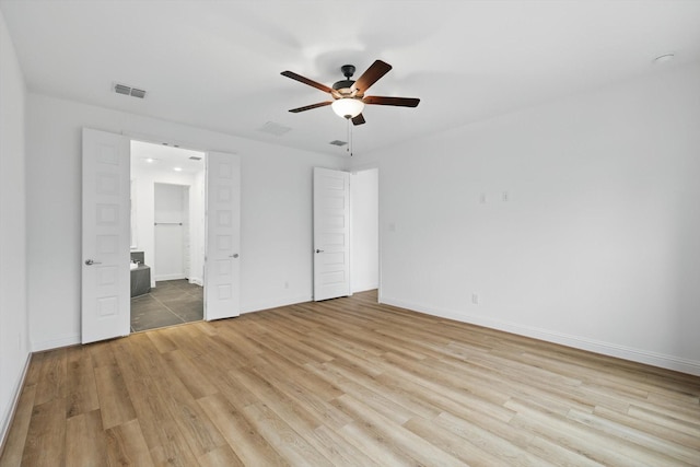 unfurnished bedroom with baseboards, ensuite bathroom, visible vents, and light wood-style floors