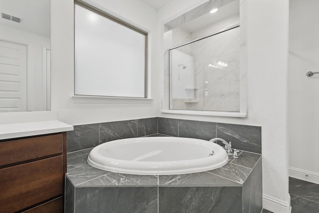 bathroom featuring a shower, a garden tub, visible vents, vanity, and baseboards