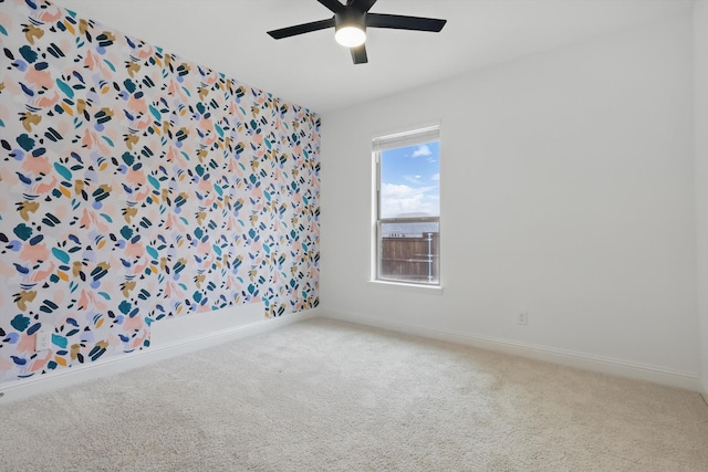 carpeted empty room with baseboards and a ceiling fan