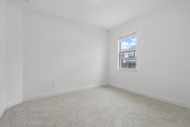 spare room with baseboards and carpet flooring