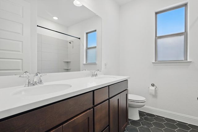 bathroom featuring double vanity, a sink, toilet, and baseboards