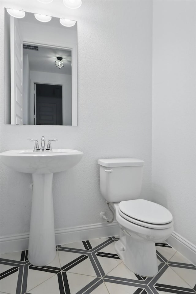 bathroom with tile patterned flooring, toilet, and baseboards