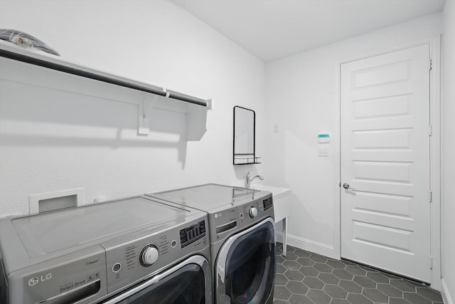 laundry room with a sink, laundry area, independent washer and dryer, dark tile patterned floors, and baseboards