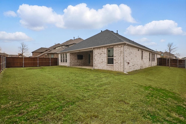 back of house with a yard, brick siding, a patio, and a fenced backyard