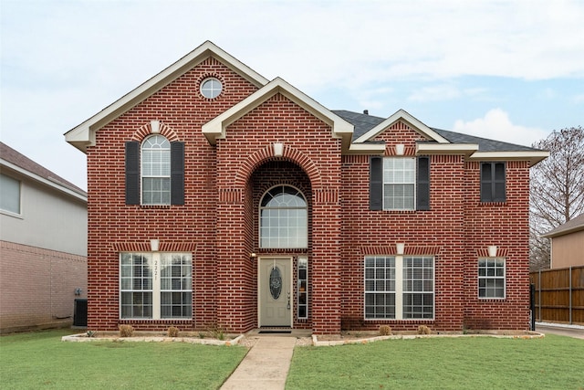 traditional home with a front lawn, fence, and brick siding