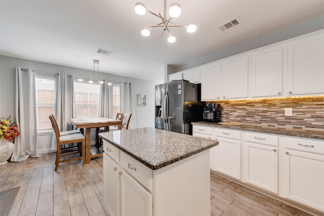 kitchen with backsplash, a kitchen island, stainless steel fridge, and visible vents