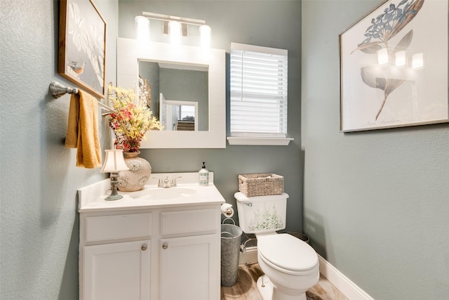 bathroom with baseboards, vanity, toilet, and wood finished floors