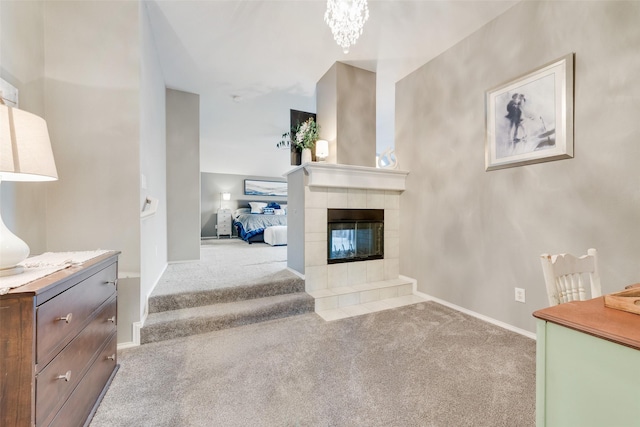 unfurnished living room with carpet floors, baseboards, a chandelier, and a tile fireplace