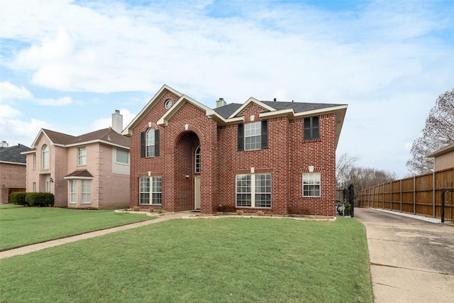 view of front facade featuring brick siding, a chimney, a front yard, and fence