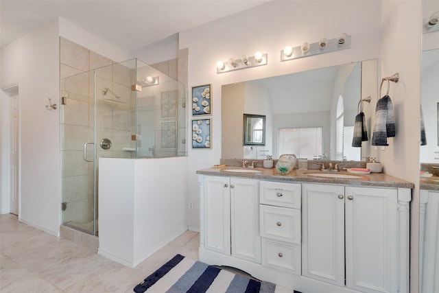 bathroom featuring double vanity, a shower stall, and a sink