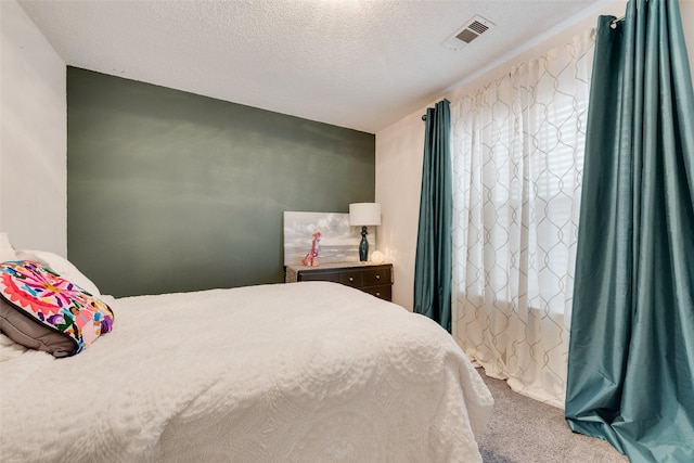 bedroom with carpet, visible vents, and a textured ceiling