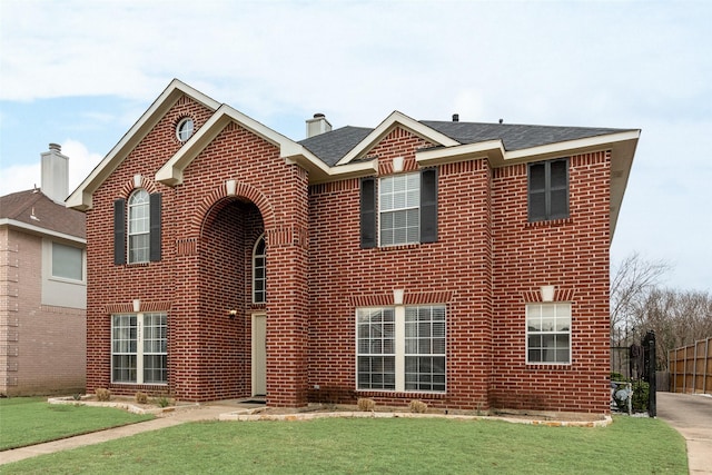 traditional-style house featuring a chimney, fence, a front lawn, and brick siding