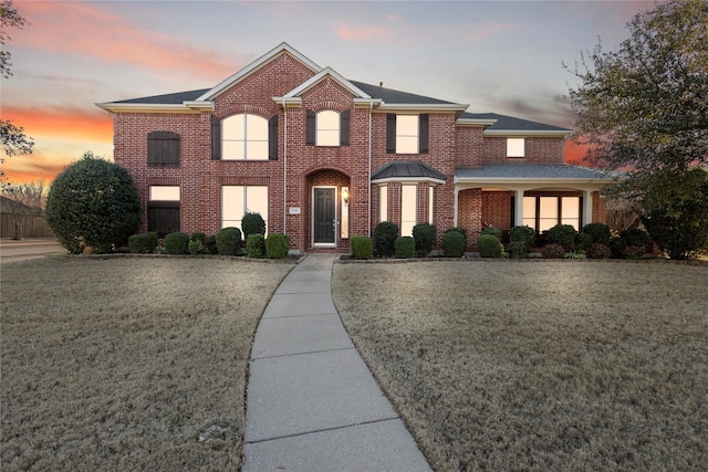 view of front of house featuring brick siding and a front lawn