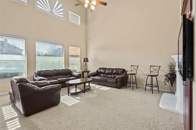 living area with a towering ceiling, baseboards, a ceiling fan, and carpet flooring