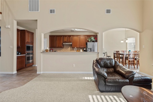 living room with visible vents, a towering ceiling, and light tile patterned floors