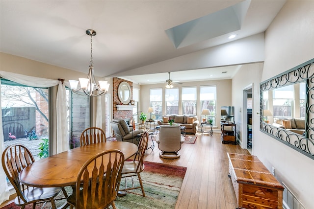 dining space with visible vents, wood-type flooring, vaulted ceiling, a brick fireplace, and recessed lighting