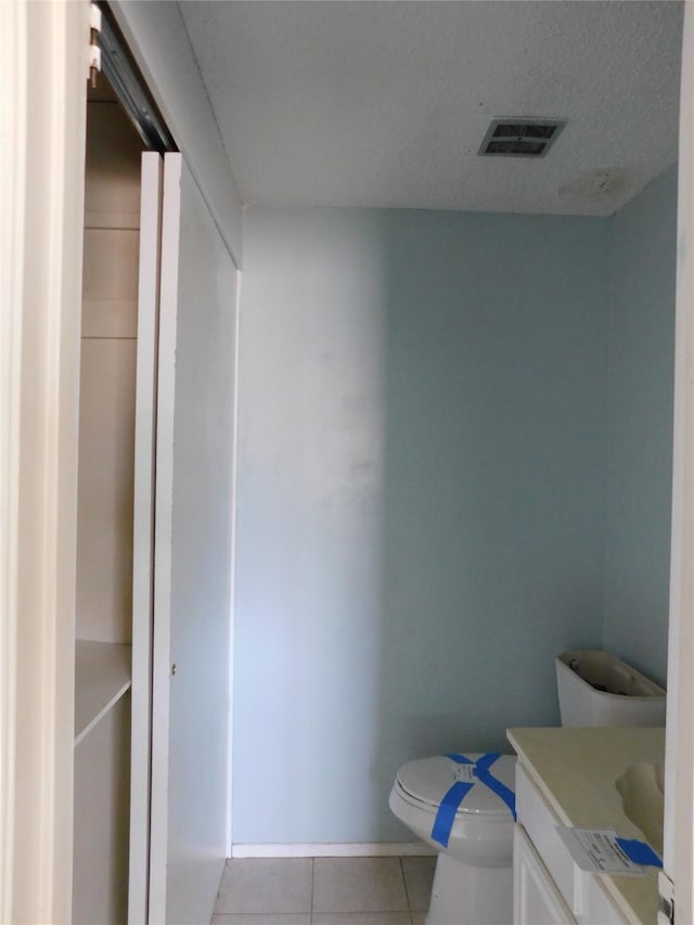 bathroom with visible vents, toilet, a textured ceiling, vanity, and tile patterned floors