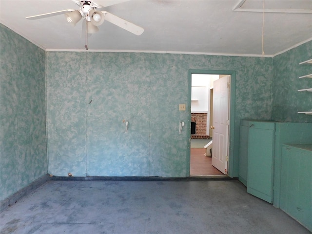 unfurnished room with attic access, ceiling fan, ornamental molding, concrete floors, and a fireplace