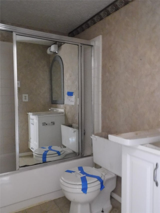 bathroom featuring enclosed tub / shower combo, vanity, toilet, and tile patterned floors