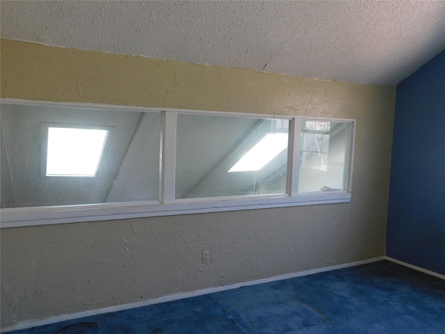 carpeted empty room with baseboards, a textured ceiling, and a textured wall